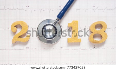 Stethoscope w/ 2018 gold wooden number on ECG background. Creative idea for new trend in medicine treatment and diagnosis concept. Happy New Year for healthcare and medical banner/calendar cover.