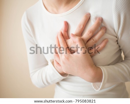 Heart attack/problems. Young female suffering from severe chest pain. Warning signs of unstable angina or myocardrial infarction disease. Health care and cardiological concept. Close up. Copy space.