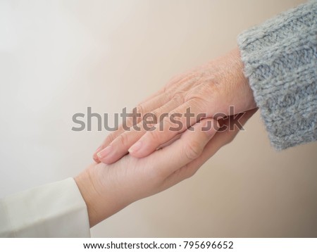 Health care for elderly person, Parkinson\'s disease, Alzheimer\'s disease, dementia and disability person. Close up of young doctor/caregiver hands holding senior patient hands for helping/supporting.