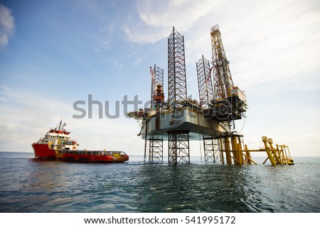 Supply Vessel Alongside Offshore Jack Up Drilling Rig Over The Production Platform in The Middle of The Sea