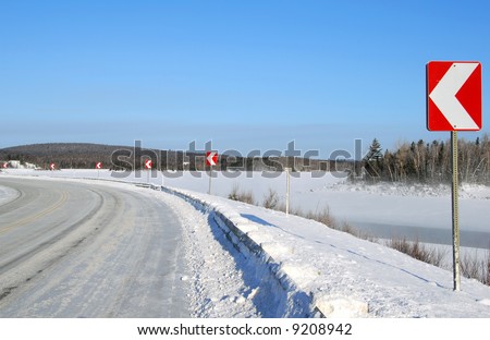 Winter road turning left with many direction signs