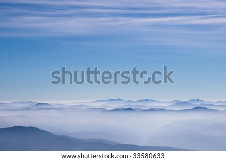 Blue mountains on a horizon with gentle blue sky with clouds