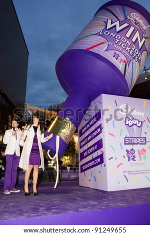 LONDON UK - DECEMBER 20: Christine Bleaky launches a giant party popper containing Olympic 2012 tickets on unsuspecting shoppers in East Londons Westfield  on the December 20, 2011 in London, UK