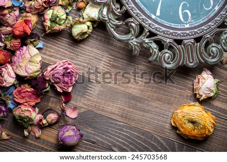 Abstract holiday frame with rose petals and dried flowers on old wooden plates.