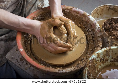 The hands of a potter, creating an earthen jar on the circle, close-up
