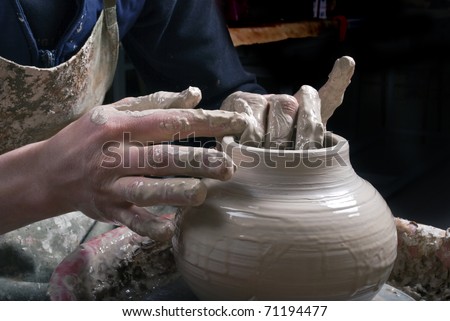 Potter at work creating clay bowl on turning wheel