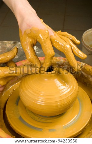 hands of a potter, creating an earthen jar of red clay