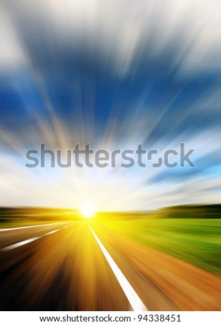 Blurred road and blue blurred sky with a shining sun