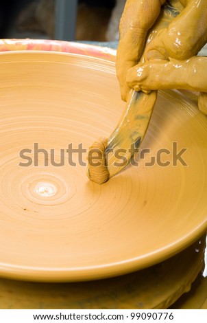 hands of a pohands of a potter, creating an earthen jar on the circletter