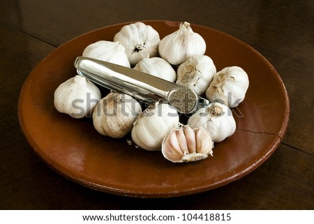 Garlic and garlic press on an old ceramic plate