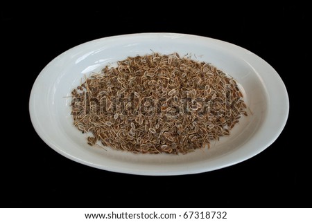 Dry dill seed on white plate in isolated on black