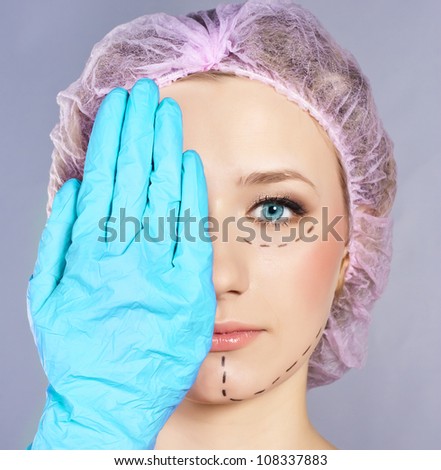Plastic surgery hand touching the beautiful woman face.  Model is european beauty