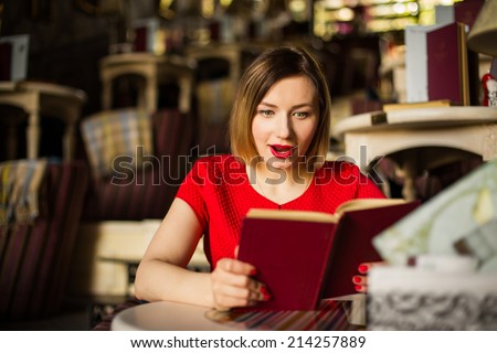 Surprised woman in a cafe reading a book
