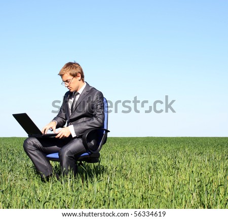 Businessman relaxing on green grassland.Under blue sky