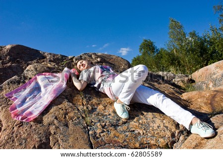 Positive young girl against the rock in summer