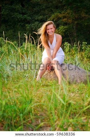pretty woman in white dress sitting on big stone