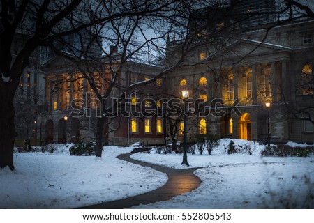 Queen street park in Toronto, Ontario, Canada in the winter, the grass covered in snow. Osgoode Hall building in the park has lights