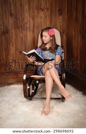 The girl in the ancient rocking-chair standing on fur reads the book