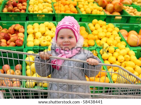 The girl with a basket in shop with fruit background