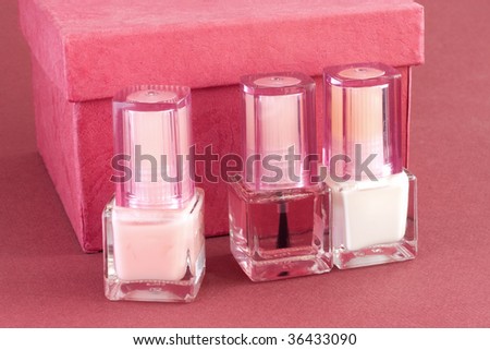 Three bottles of nail polish for French manicure and red box on red background