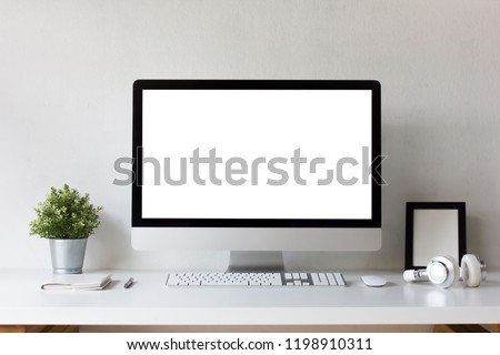Front view office table desk. Workspace with blank computer screen, keyboard, mouse, booklet, pen, headphones, picture frame isolated, plant mockup and white background