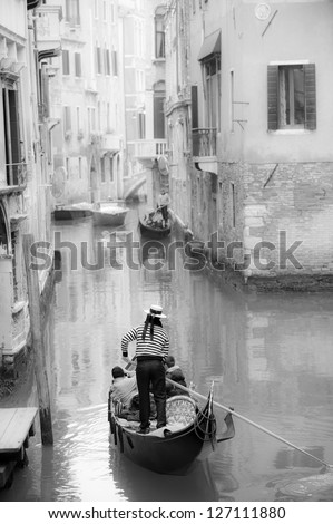 Gondolier guiding a gondola in narrow Venetian canal