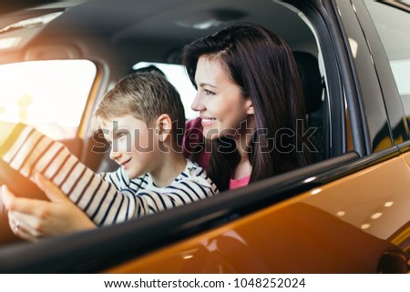 Mother and son choosing a new car to buy at the car showroom.