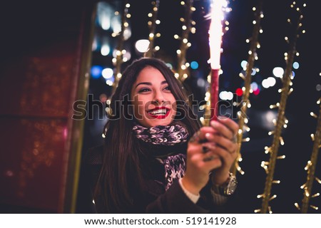 Beautiful young brunette woman with Jack Russel terrier enjoying Christmas or New Year night on a city street.