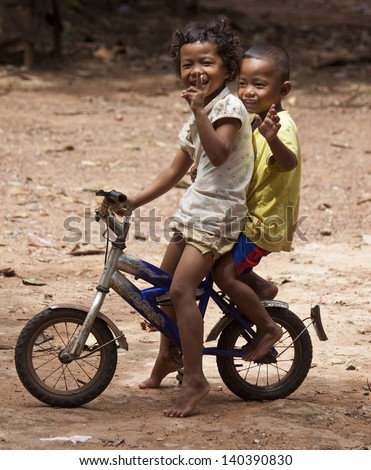 KAMPOT, CAMBODIA - JULY 21: Young unidentified children posing at bicycle in Kampot, Cambodia on July 21, 2012. With widespread poverty, Cambodian street children are not a rare sight.