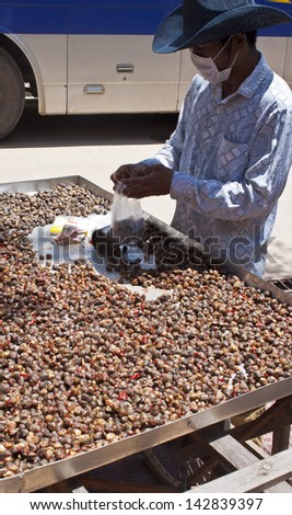 SIEM REAP, CAMBODIA - JULY 14:  Unknown man sells snails in Siem Reap, Cambodia on July 14, 2012. Cambodians eat many types of unusual food as snails, frogs, snakes or spiders.