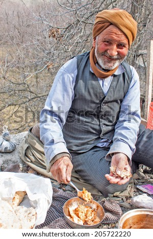 KANG, IRAN - FEBRUARY 24: Old village man eats his lunch on February 24, 2013 in a village Kang, Iran. Kang is a small stepped village in northern Iran.