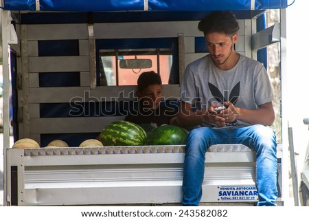 NAPLES, ITALY- JULY 1, 2014: Two young men ride in a van with vegetables in Naples, Italy. There are many small shops selling fruits and vegetables in the center of Naples.