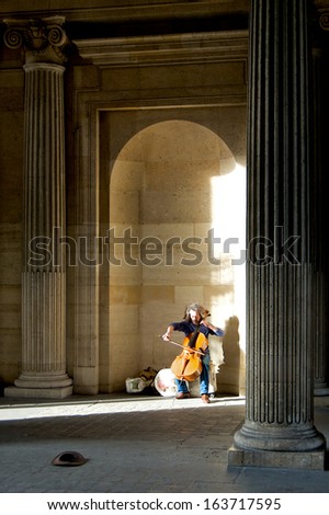 PARIS - SEPTEMBER 19: Man playing his cello for money at the Louvre museum, the world\'s most visited museum, with over 8 million visitors a year, in Paris, France, on September 19, 2013.