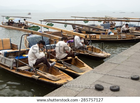 HANGZHOU, CHINA - MAY 3, 2015: Traditional Chinese wooden boats with boatmen on the Xihu (West Lake) taking a break and having some lunch. The lake has influenced poets and painters throughout China.