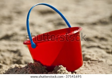 Plastic Red Pail With a Blue Handle in the sand