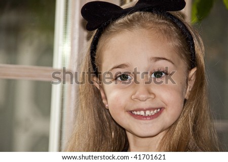 Little Blond Girl With Her Hair pushed back with a headband and a huge smile