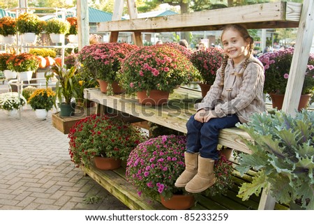 Little Girl Sitting On a display of Mums