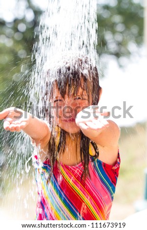 Happy little  girl enjoying in summer day and playing with water