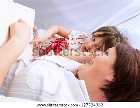 A mother and her little daughter reading a book before sleeping