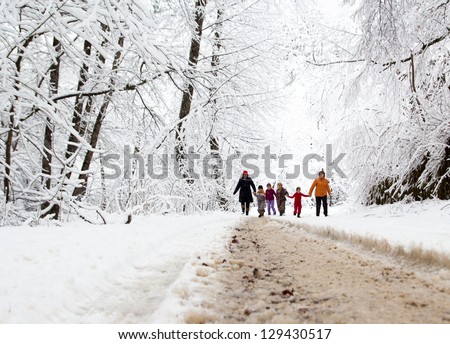 Happy family winter fun outdoors. Active parents with kids running in snowy forest