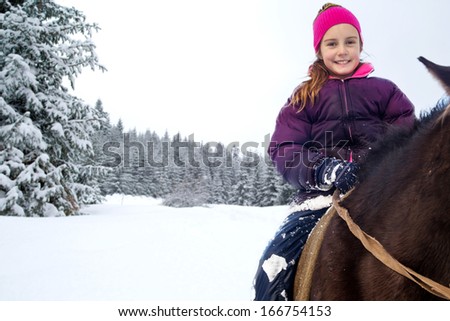 Little girl riding horse in winter
