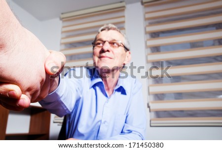 Senior businessman shaking someone\'s hand and smiling