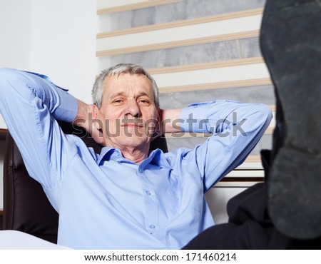 Senior businessman lying on his office chair with his feet on the desk