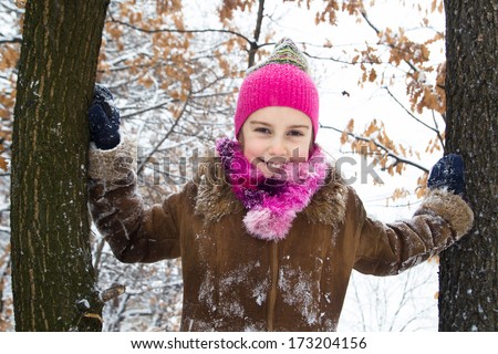 Happy little girl spending a nice time in winter forest
