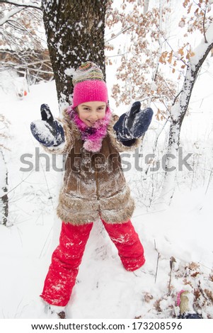 Happy little girl spending a nice time in winter forest