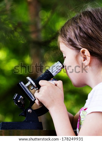 student little girl with microscope - working outside in nature