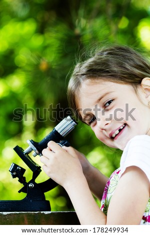 student little girl with microscope - working outside in nature