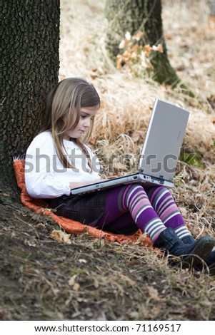 Little girl with laptop in forest