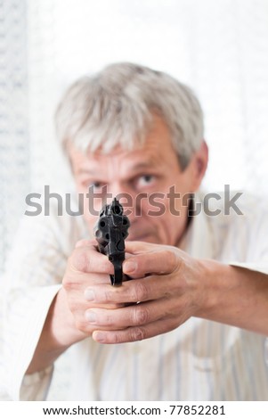 Older angry man aiming with gun and ready to fire