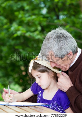 Grandfather spending time with little girl outside-little girl learning to write